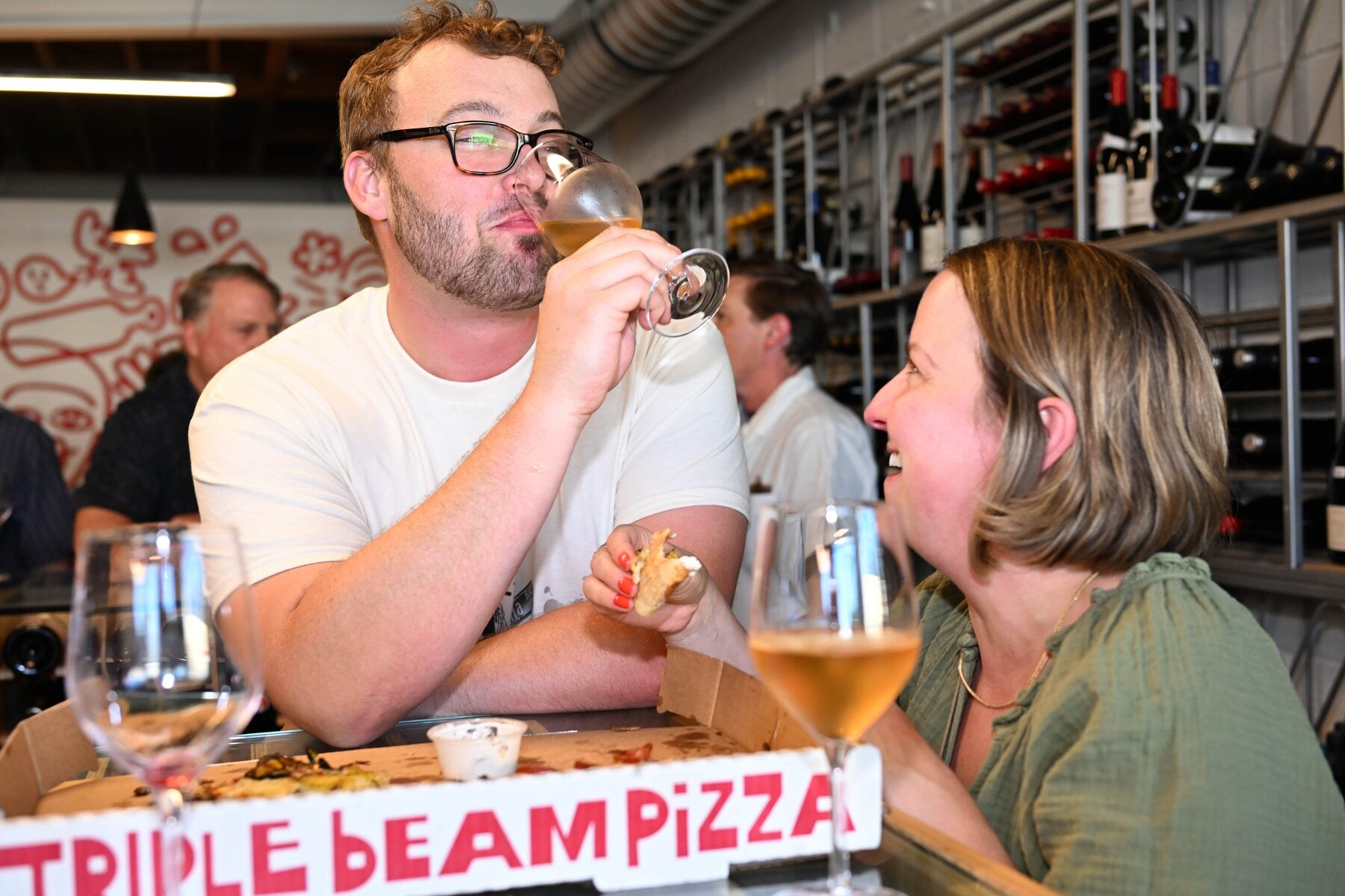Customer enjoying wine + Triple Beam pizza