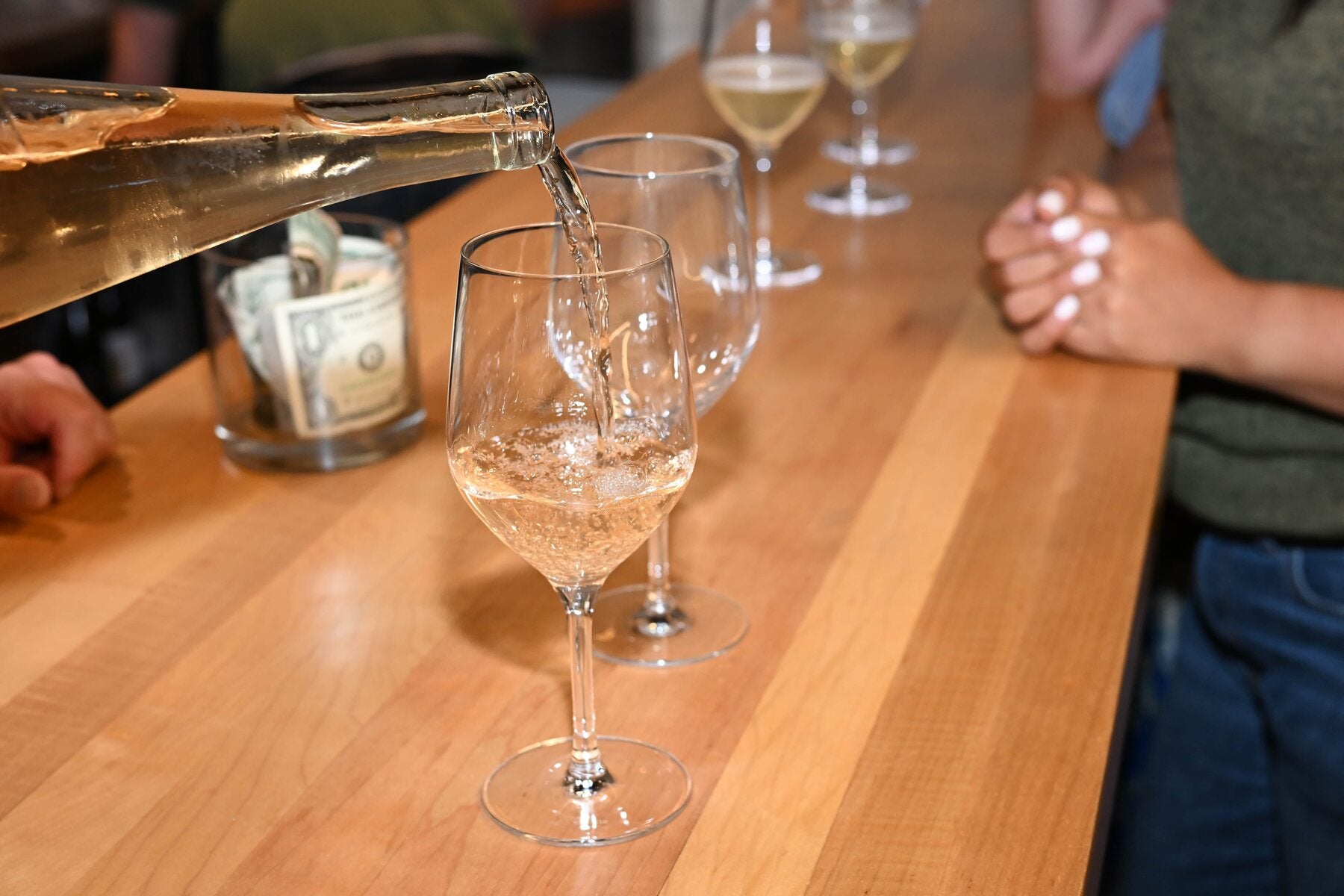 A bottle being poured into a wine glass at the bar